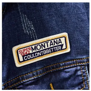 Detailed macro shot of an embroidered vintage Montana patch on a blue denim jacket