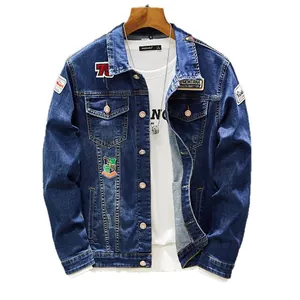 Men's slim fit blue denim jacket with stylish embroidered patches on a white background.