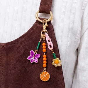 Détail d'un bijou de sac coloré avec fleurs et tranche d'orange sur une bandoulière