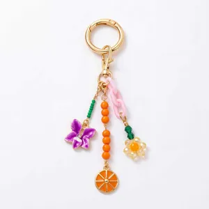 Gros plan d'un porte-clés coloré avec des breloques de fleurs et d'orange dorées