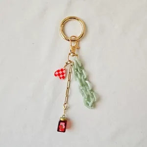 Détail du porte-clés DIY avec cœur, chaîne verte et mini pot de confiture de fraises