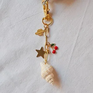 Vue détaillée du porte-clés plaqué or 18 carats avec breloques coquillage, cerise et cactus