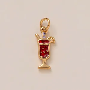 Vue détaillée d'un pendentif en forme de verre à cocktail doré avec émail rouge et cristaux