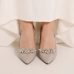 Primo piano di eleganti clip per scarpe con strass argento su décolleté grigie a spillo