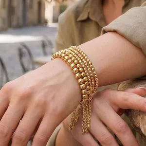 Close-up of four-layer stackable gold bead bracelets featuring varying bead sizes