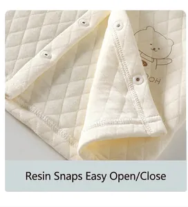 Vue détaillée des boutons-pression en résine sur un gilet matelassé doux pour bébé