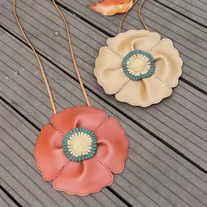 Detailed view of cute flower-shaped kids soft leather crossbody bags in rust and tan