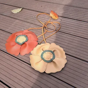 Two flower shaped leather crossbody bags for kids on a wooden deck background