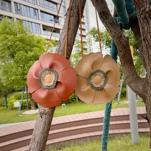 Detailed view of two cute flower-shaped children's crossbody bags hanging on a tree branch