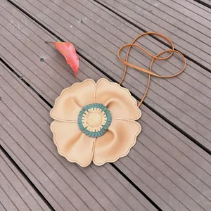 Close-up detail of a cute tan flower-shaped children's bag on a rustic wooden platform