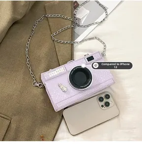 Macro view of purple camera-shaped hard case crossbody bag next to a smartphone