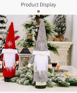 Fundas festivas para botellas de vino de gnomos navideños rojos y grises sobre una mesa