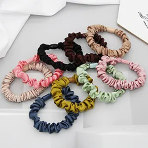 Detailed view of multiple colorful satin silk scrunchies on white display stands.