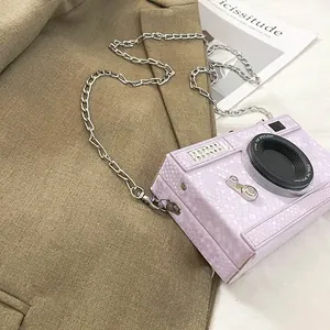 Close-up of a lavender snakeskin camera-shaped box bag with a silver chain strap.