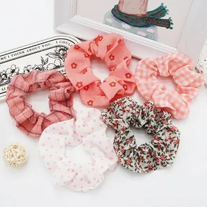Detailed view of five assorted floral, polka dot, and gingham fabric hair scrunchies