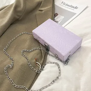 Close-up detail view of lavender snakeskin pattern box bag with silver chain strap