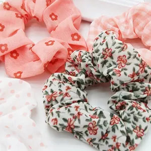 Close-up of assorted floral, polka dot, and gingham fabric scrunchies for hair.