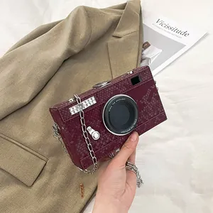 Detail view of retro wine red snakeskin camera shaped box bag with metal chain strap