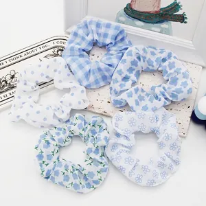 Collection of five blue and white floral and polka dot fabric scrunchies on white stone