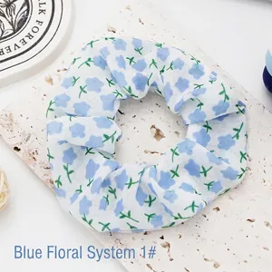 Detailed macro view of a white fabric scrunchie with blue floral print on stone base