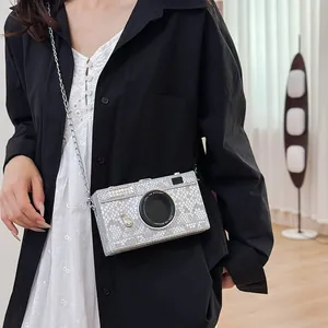 Silver snakeskin pattern camera-shaped crossbody bag worn by a model in a black shirt
