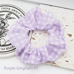Detail view of a purple and white gingham fabric hair scrunchie for women styling