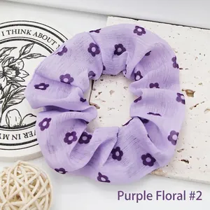 Macro view of purple floral fabric scrunchie showing delicate flower pattern and texture