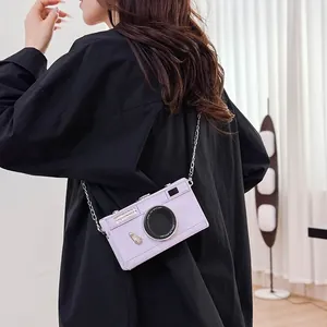 Detail view of a vintage purple camera-shaped box crossbody bag on a model