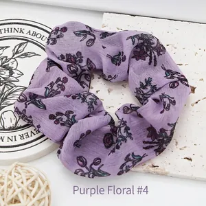 Detailed close-up of a purple floral print fabric scrunchie hair tie accessory