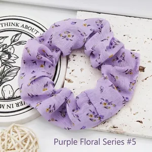 Purple chiffon scrunchie with small floral print on textured stone background