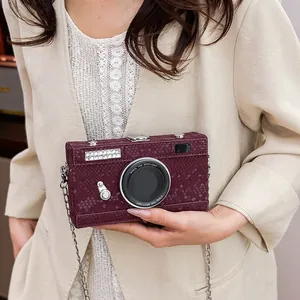 Detail of a vintage camera-shaped hard box crossbody bag with snakeskin texture
