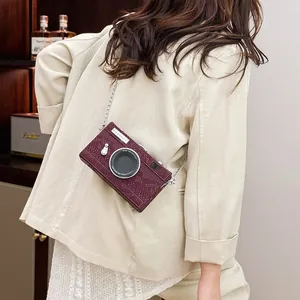 Retro burgundy camera-shaped hard box crossbody bag styled on a beige blazer