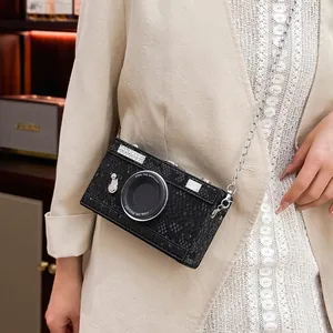 Close-up of vintage camera-shaped hard box crossbody bag with black snakeskin texture