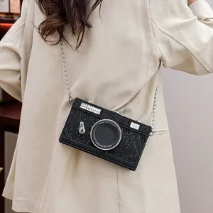 Close-up of a vintage black camera-shaped crossbody bag with a textured finish.