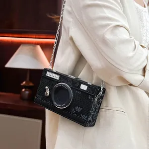 Close-up of a vintage camera-shaped crossbody bag with snakeskin texture on a model