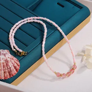 Hochwertige Nahaufnahme einer Perlenkette mit rosa Bambusgliedern auf blauem Samttablett