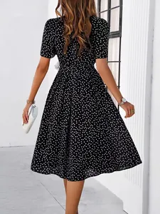 Back view of elegant black polka dot midi dress featuring short sleeves and a pleated skirt.