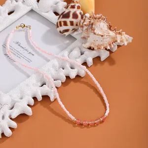 Detaillierte Nahaufnahme einer rosa Muschelperlenkette mit Perlen und rosa Steinen.