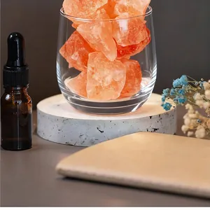 Close-up of natural pink crystal diffuser stones in a clear glass with an essential oil bottle