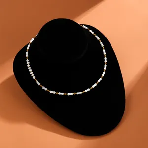 Detailansicht einer weißen Muschelperlenkette mit goldenen Akzenten auf schwarzem Ständer
