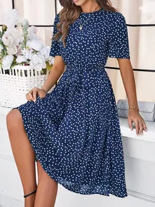 Close-up detail of a navy blue polka dot midi dress showing the waist tie and fabric texture.