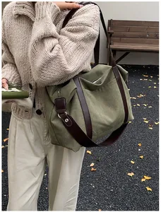 Grande borsa tote in tela verde oliva con cinturini in pelle marrone su un modello