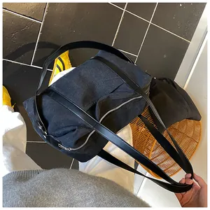 Vista dall'alto di una borsa sottobraccio minimalista in denim nero con manici neri lisci