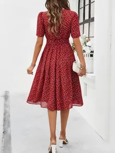 Back view of a red polka dot midi dress featuring short sleeves and a flared skirt design