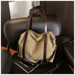 Vista dettagliata della borsa tote in tela verde oliva con manici in pelle marrone