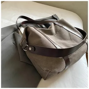 Dettaglio di una grande borsa tote in tela con tracolle in pelle marrone