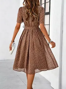 Detail view of a brown polka dot midi dress with waist tie and A-line pleated skirt