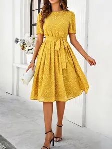 Full-length view of a vibrant yellow polka dot midi dress with an elegant waist tie.