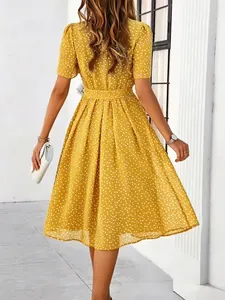 Back view of elegant yellow polka dot midi dress with pleated skirt and waist belt.
