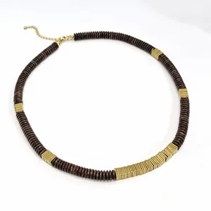Detail shot of a coconut shell necklace with golden copper alloy spacers on white background.